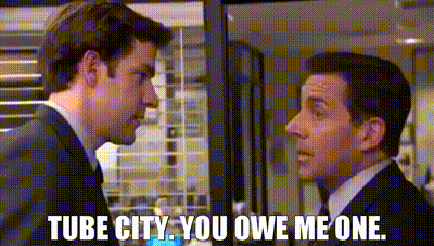 two men in suits are standing next to each other and one of them is saying `` tube city . you owe me one . ''