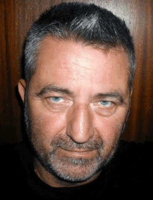 a man with a beard is looking at the camera with a serious look on his face