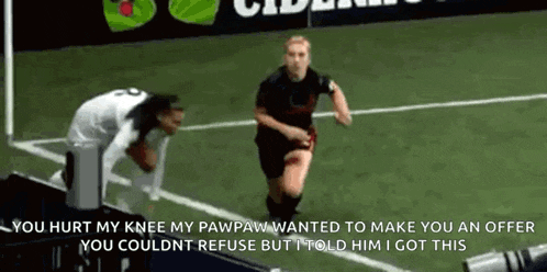 a woman is running on a soccer field while a man is kneeling on the ground .