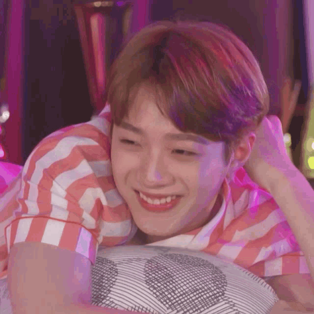 a young man is smiling while laying on a pillow