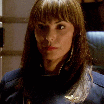 a close up of a woman wearing a blue uniform with a gold badge