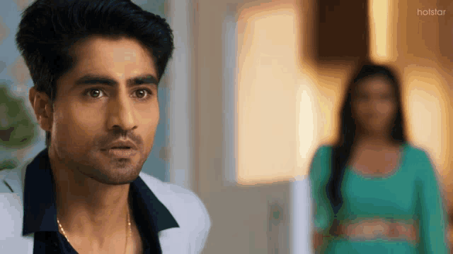 a man in a white jacket stands in front of a woman in a green dress ..