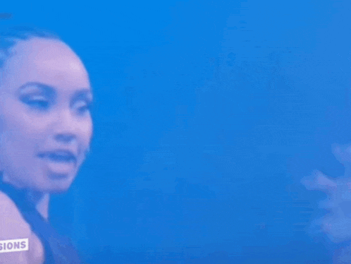 a woman is singing into a microphone with a sign that says ' sions ' on it