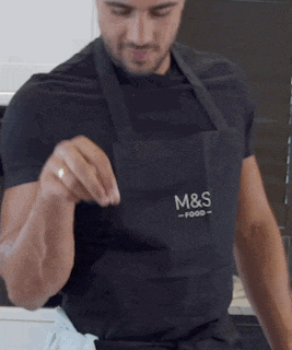 a man wearing an apron that says m & s food on it