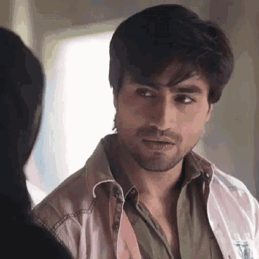 a man with a beard is looking at a woman while wearing a pink shirt .