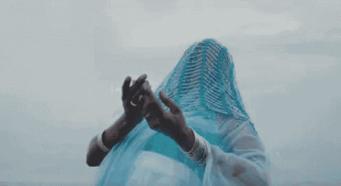 a woman in a blue dress with a veil on her head is dancing .
