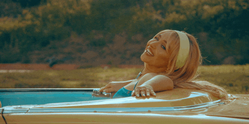 a woman in a bikini is laying in the back of a yellow car