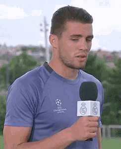 a man in a blue shirt is holding a microphone in his hand .