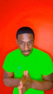 a man in a green shirt is clapping his hands against a red background