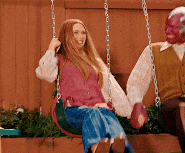 a woman is sitting on a swing next to a man in a mask
