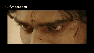 a close up of a man 's face with a tattoo on his forehead
