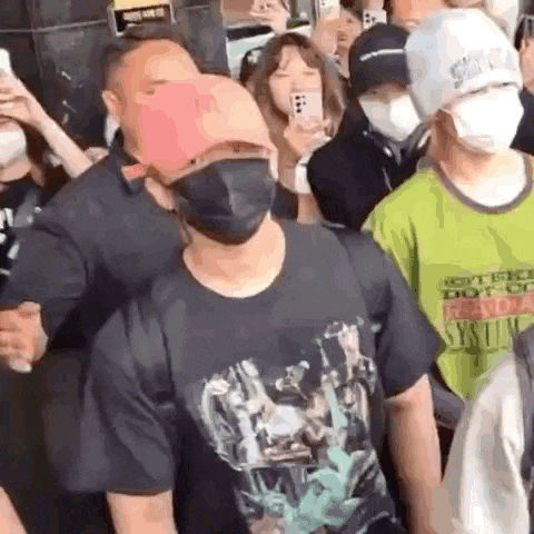 a man wearing a mask and a hat is surrounded by a crowd of people .