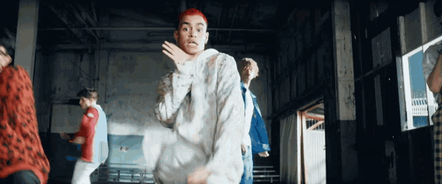 a man with red hair is dancing in a warehouse