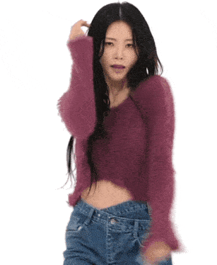 a woman in a purple sweater and blue jeans is dancing in front of a white background .