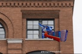 a brick building with a cartoon character flying out of a window