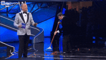a man in a suit is dancing on a stage with a blue background .