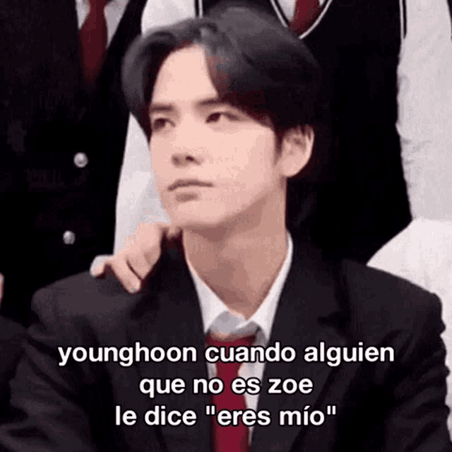 a man in a suit and tie with a caption that says younghoon cuando alguien que no es zoe le dice eres mio
