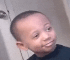 a young boy is smiling and looking at the camera while standing in front of a door .