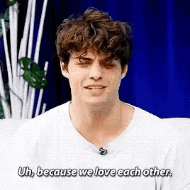 a young man is sitting on a couch and saying `` uh , because we love each other . ``