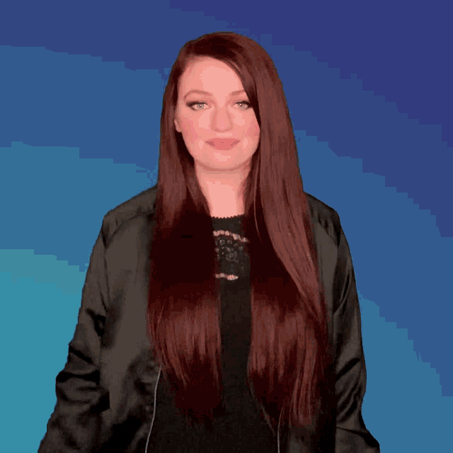 a woman with long red hair wearing a black jacket and a black top