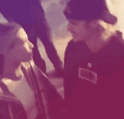 a man in a baseball cap is kissing another man on the cheek in a blurry photo .