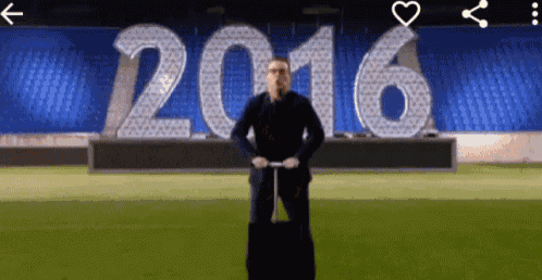 a man with a suitcase stands in front of a 2016 sign