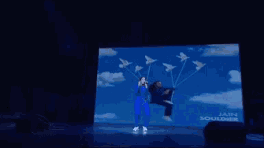 a man in a blue suit is flying through the air while holding a balloon