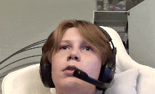 a young boy wearing headphones and a microphone is sitting in a white chair .