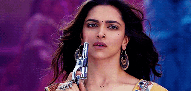 a woman is holding a gun in front of her face ..