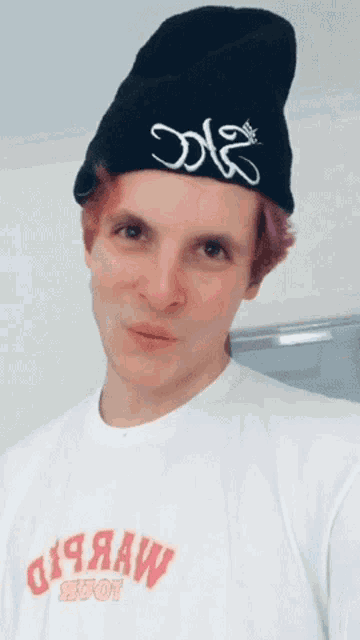 a young man wearing a black beanie and a white shirt that says ' a ' on the front