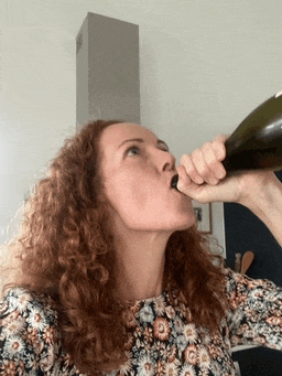 a woman drinking from a bottle with her tongue sticking out