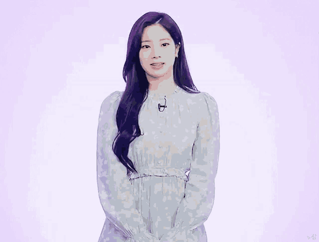 a girl with long purple hair is wearing a polka dot dress and standing in front of a purple background .
