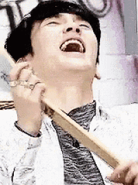 a man is laughing while holding a wooden stick in his mouth .