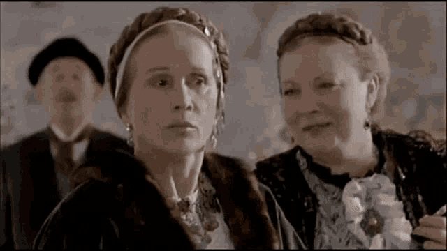 two women are standing next to each other in a room and talking to each other .