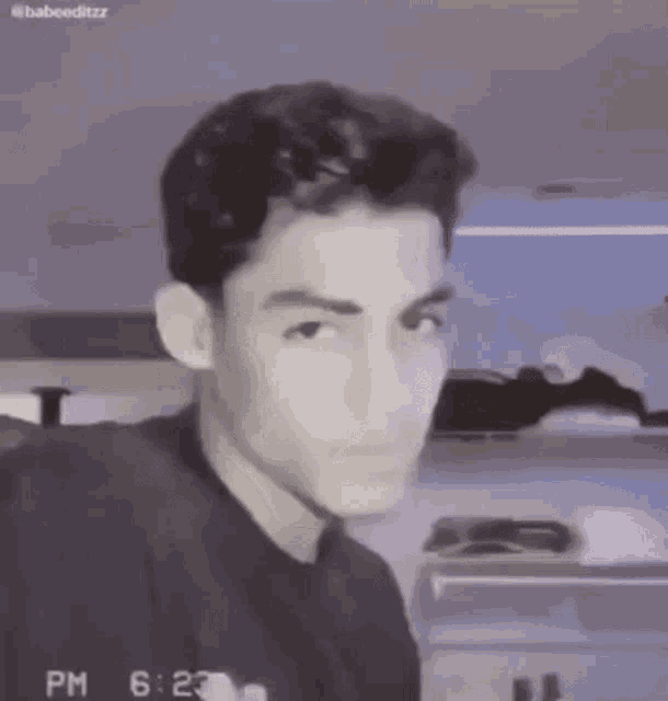 a young man in a black shirt is making a funny face .