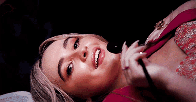 a woman is laying down with a microphone in her hand and smiling
