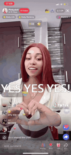 a woman with red hair is making a heart with her hands on a tiktok video