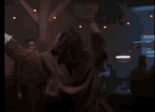 a blurry picture of a man in a dark room with his arms in the air