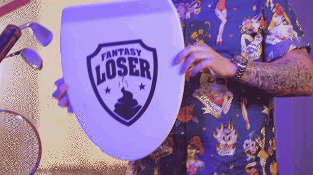 a person holding a toilet seat that says fantasy loser on it