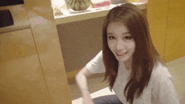 a woman in a white shirt sits on the floor in front of a counter