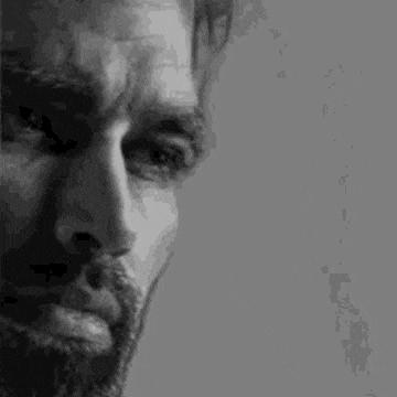 a black and white photo of a man with a beard and mustache looking down .