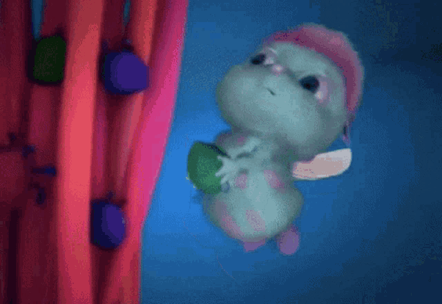 a cartoon character with a pink hat is holding a green object in its mouth