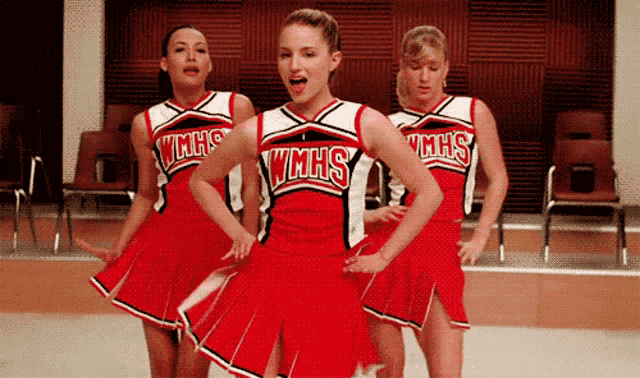 three cheerleaders wearing wmhs uniforms are performing on a stage