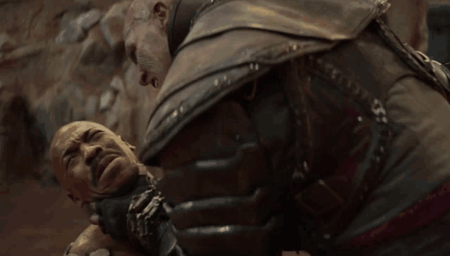 a man in a leather armor holds another man 's head