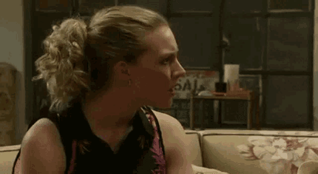 a woman is sitting on a couch with her mouth open and a ponytail .