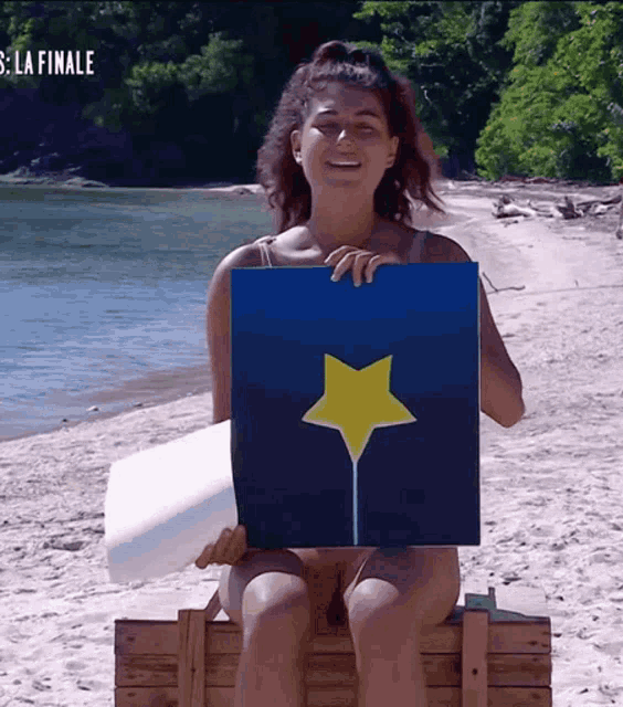 a woman sitting on a box holding a picture of a star