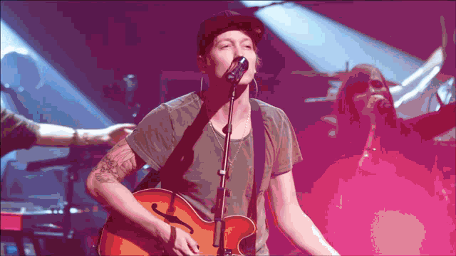 a man is singing into a microphone while holding a guitar