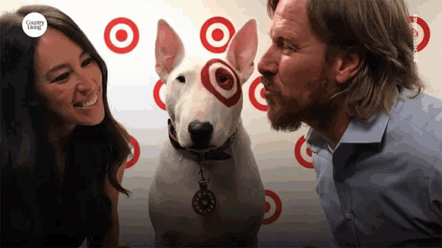 a man and a woman kissing a bull terrier in front of a target background