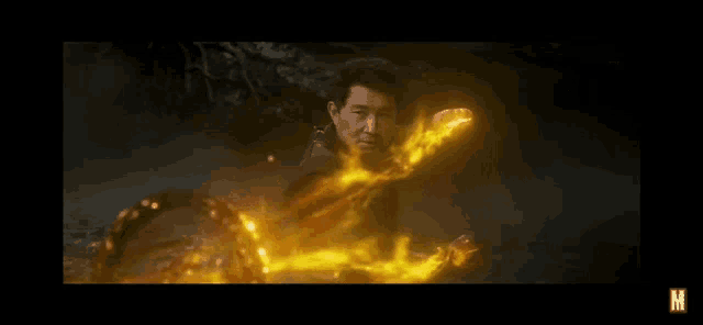 a man is holding a sword in his hand and surrounded by fire .