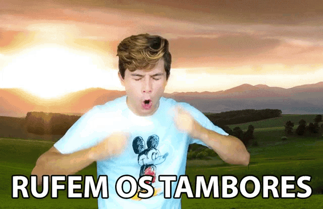 a man wearing a mickey mouse shirt with the words rufem os tambores written above him